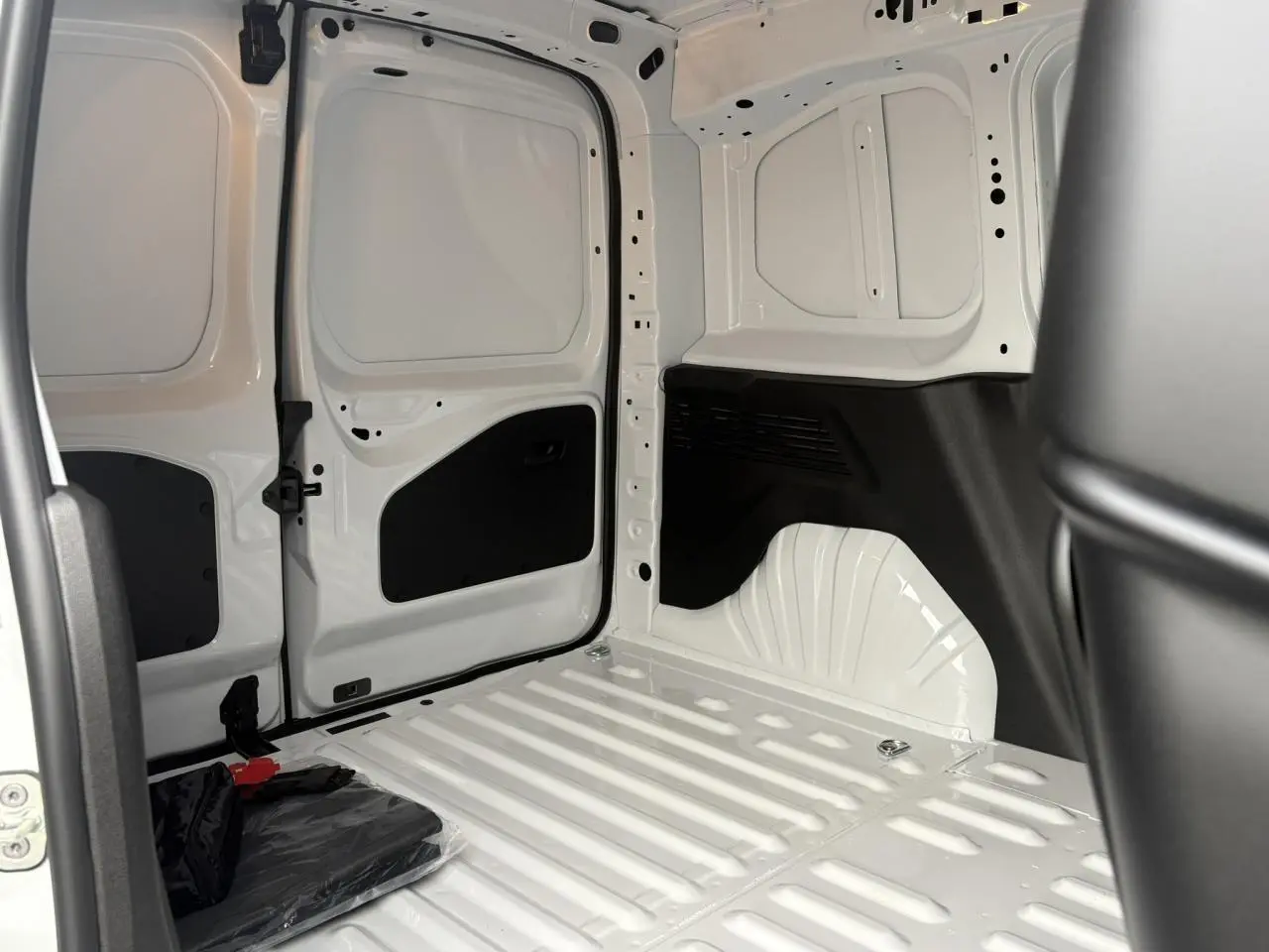 Intérieur du coffre blanc Icy du Citroën Berlingo Van 2025, vue côté droit avec cloison et espace de chargement tôlé.