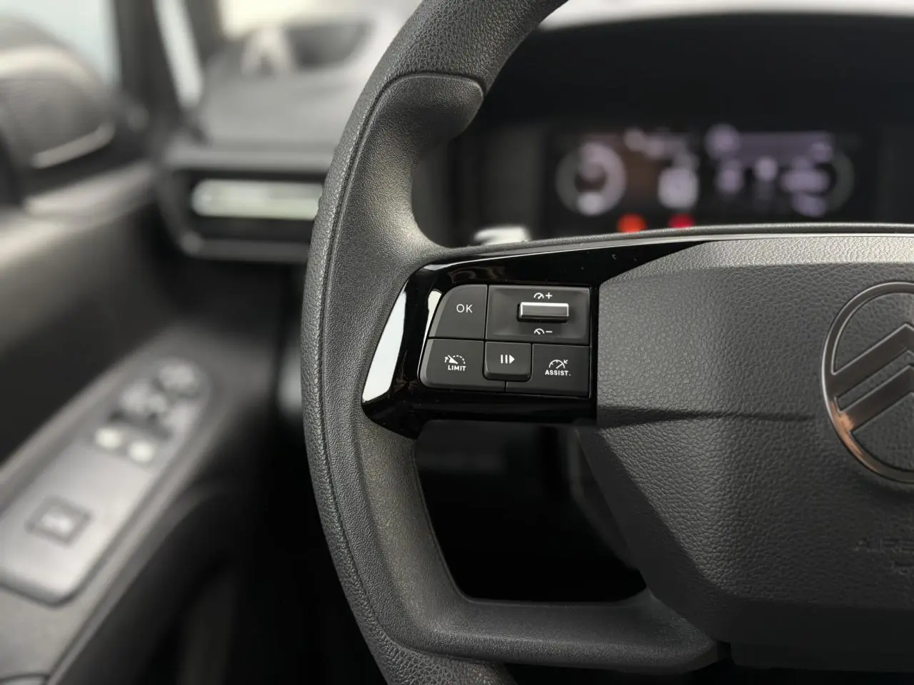 Gros plan sur le volant multifonctions noir du Citroën Berlingo blanc Icy, avec commandes de régulateur à gauche.