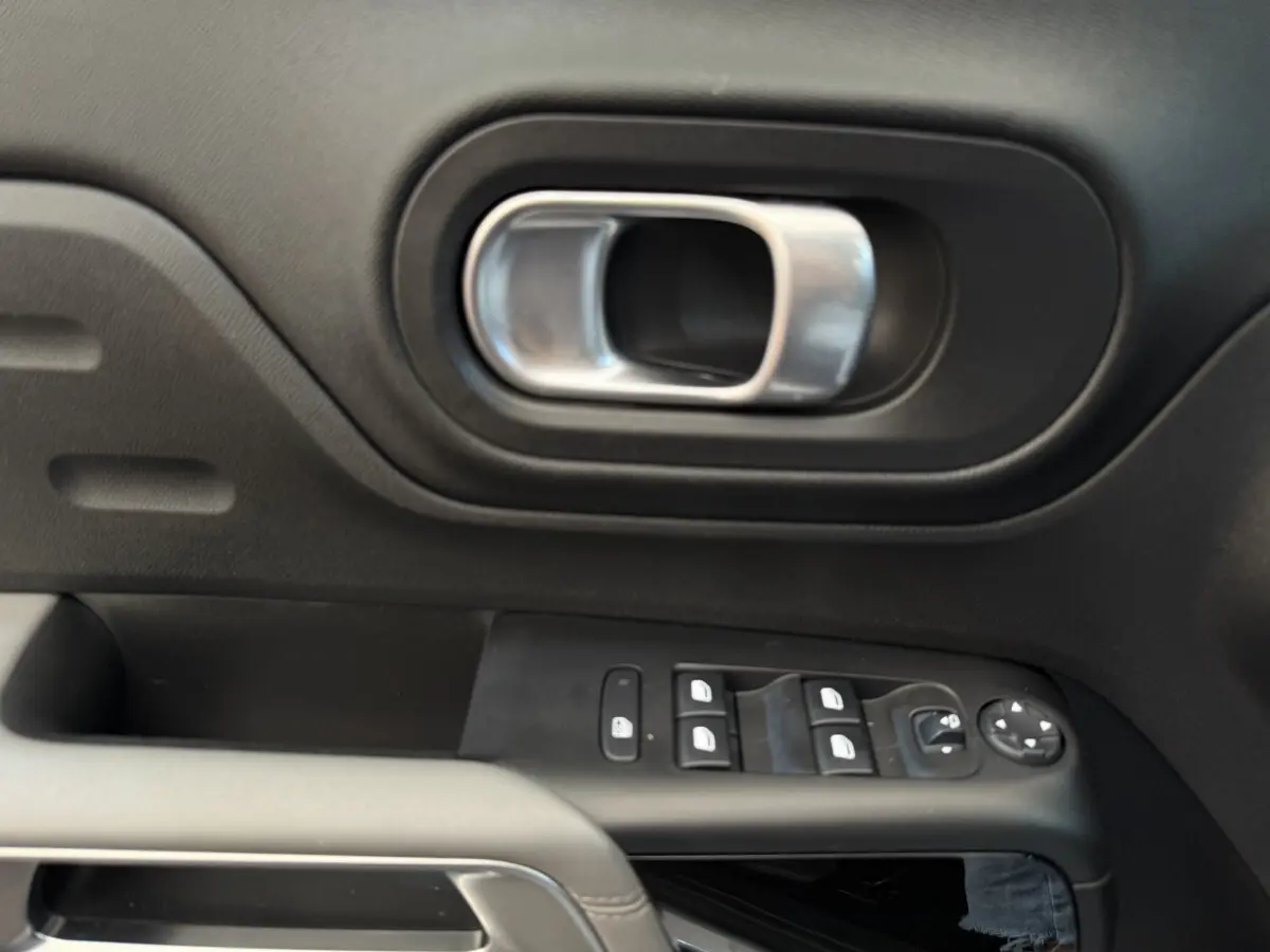 Poignée de porte intérieure et commandes des vitres côté conducteur du Citroën C5 Aircross gris clair, vue rapprochée.