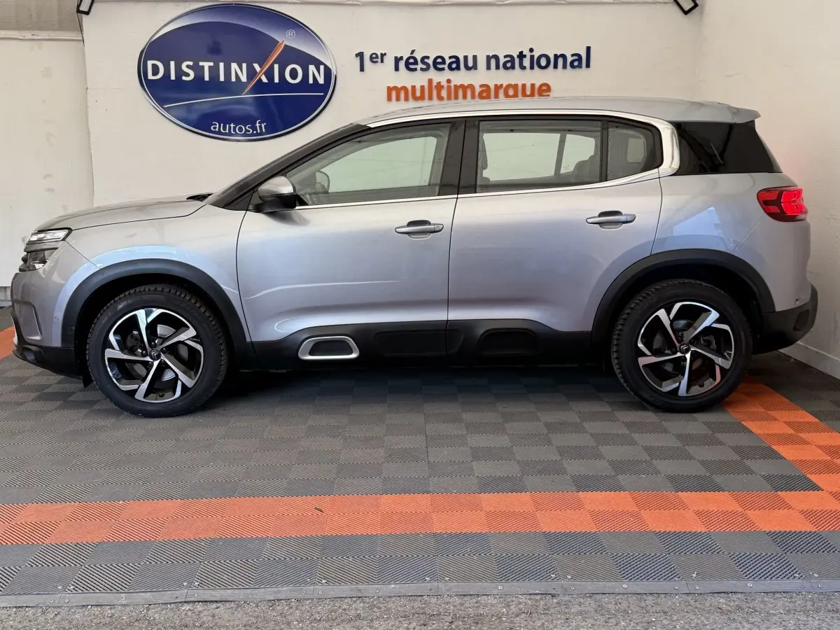 Profil côté gauche d'un Citroën C5 Aircross gris clair 2020 avec jantes alliage et toit noir contrasté.