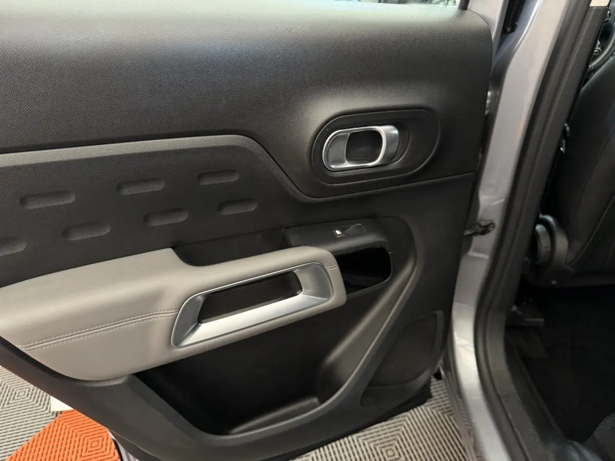 Vue intérieure de la porte arrière droite gris clair du Citroën C5 Aircross avec poignée argentée et accoudoir clair.