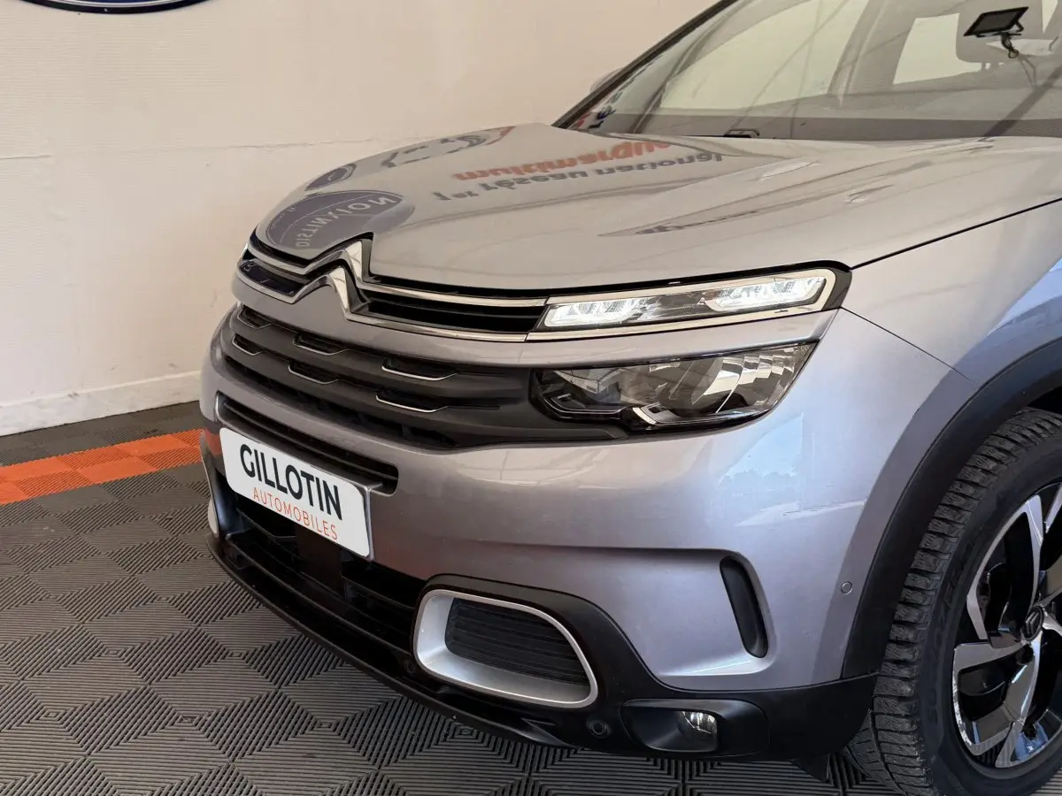 Vue avant droite du Citroën C5 Aircross gris clair, mettant en valeur ses phares LED et la calandre distinctive.