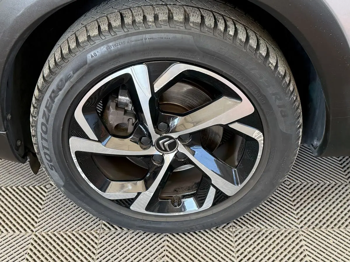 Gros plan sur la roue avant droite du Citroën C5 Aircross gris clair, avec jante alliage noire et argentée au design moderne.