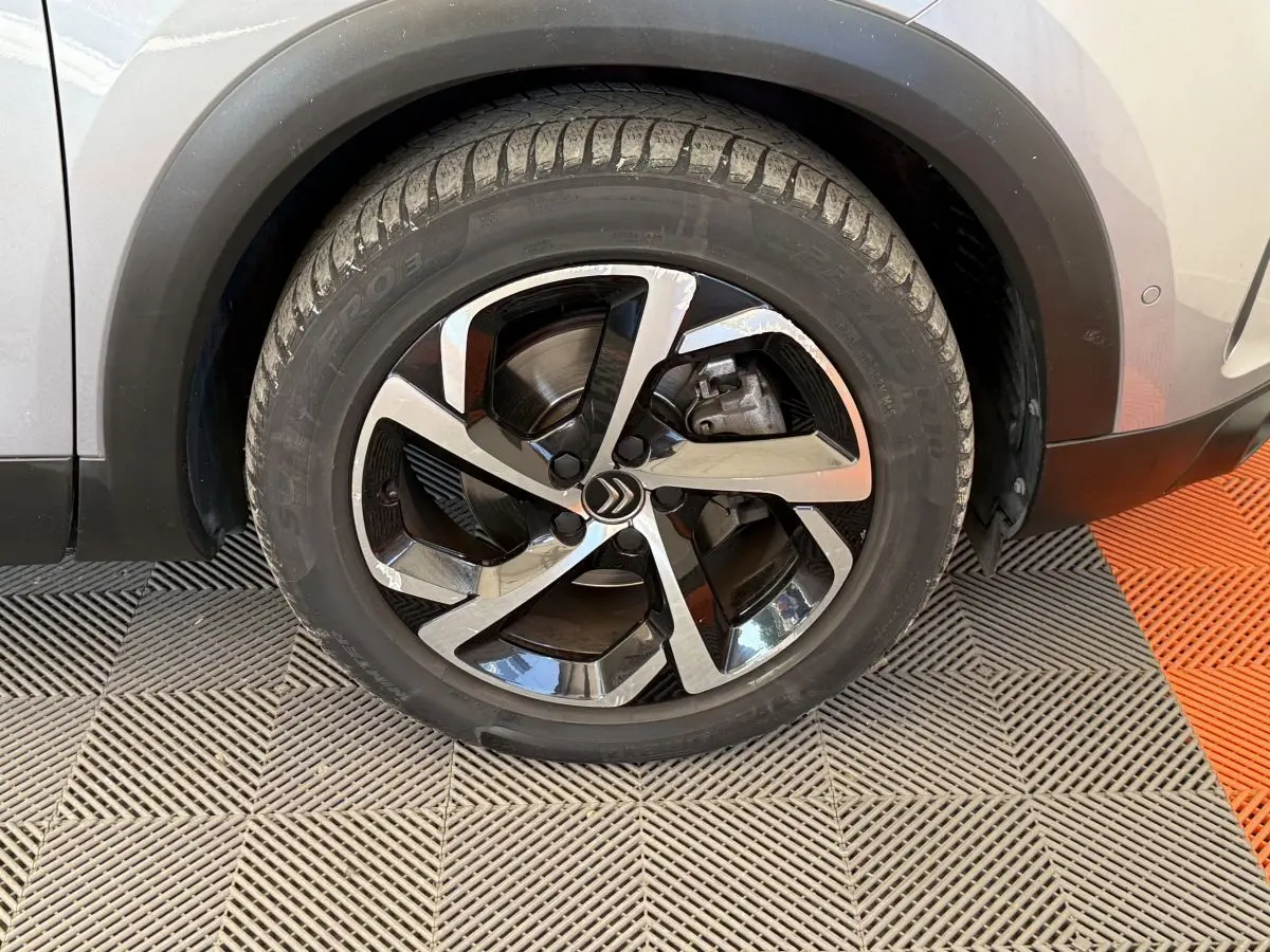 Gros plan sur la roue avant droite gris clair du Citroën C5 Aircross avec jante alliage noire et argentée.