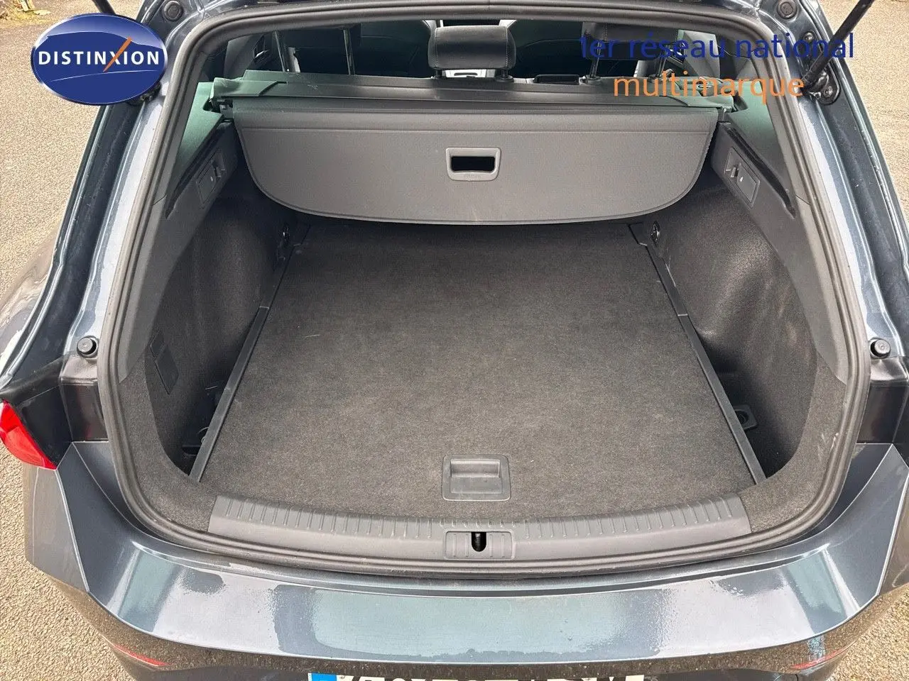 Coffre ouvert vu de l'arrière d'une CUPRA LEON ST 1.5 ETSI gris magnetic metal, montrant l'espace de chargement vide.