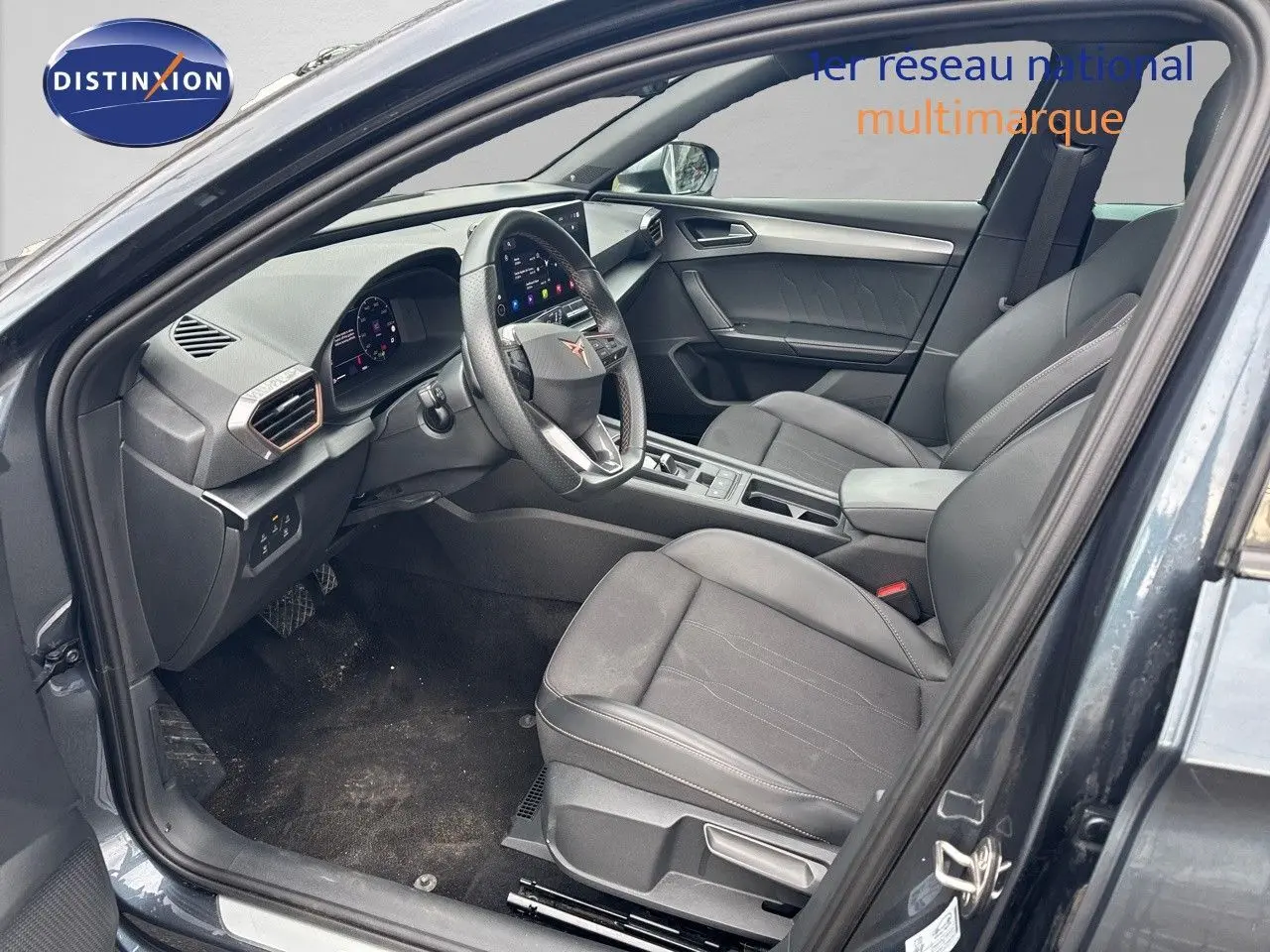 Vue intérieure côté conducteur de la CUPRA LEON ST 2024 gris magnetic, sièges en cuir noir et tableau de bord moderne.