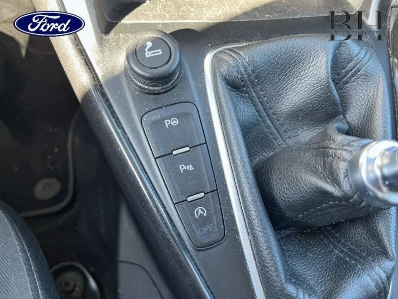 Gros plan sur la console centrale noire de la Ford Focus blanche, avec levier de vitesse cuir et boutons de contrôle.