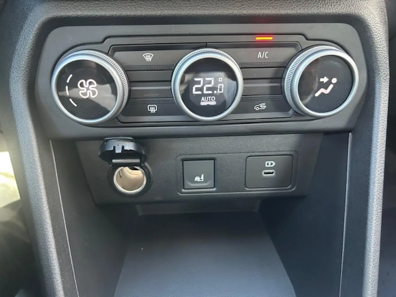 Vue rapprochée du tableau de bord de la Dacia Sandero III Stepway, montrant les commandes de climatisation et prises USB.