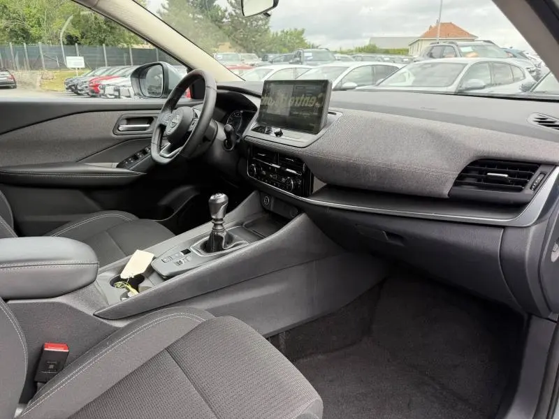 Intérieur du Nissan Qashqai 2025 gris Argile, vue côté conducteur montrant tableau de bord et console centrale avec boîte manuelle.
