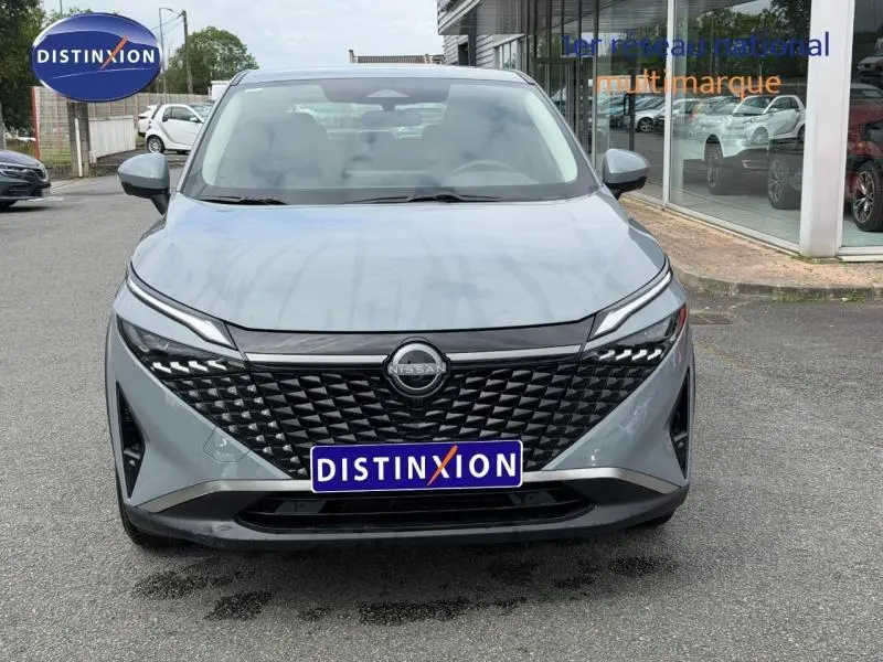 Vue frontale du Nissan Qashqai 1.3 Mild Hybrid 2025 en gris Argile avec calandre noire et phares LED distinctifs.