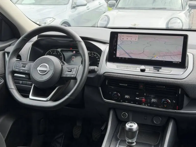 Vue intérieure du tableau de bord du Nissan Qashqai 2025 avec volant cuir multifonction et écran tactile GPS.