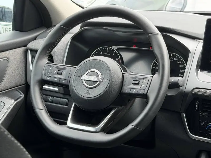 Vue rapprochée du volant cuir multifonction noir du Nissan Qashqai 2025 avec commandes intégrées et tableau de bord visible.