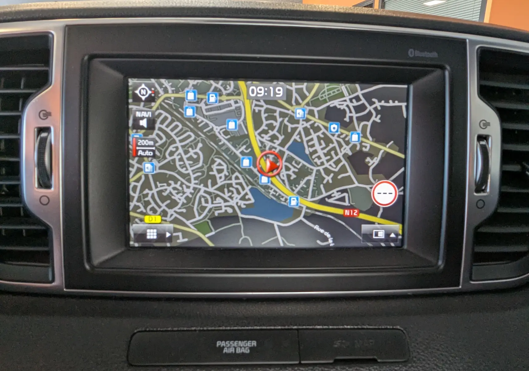 Écran de navigation GPS intégré au tableau de bord d’un Kia Sportage gris, vue frontale rapprochée.