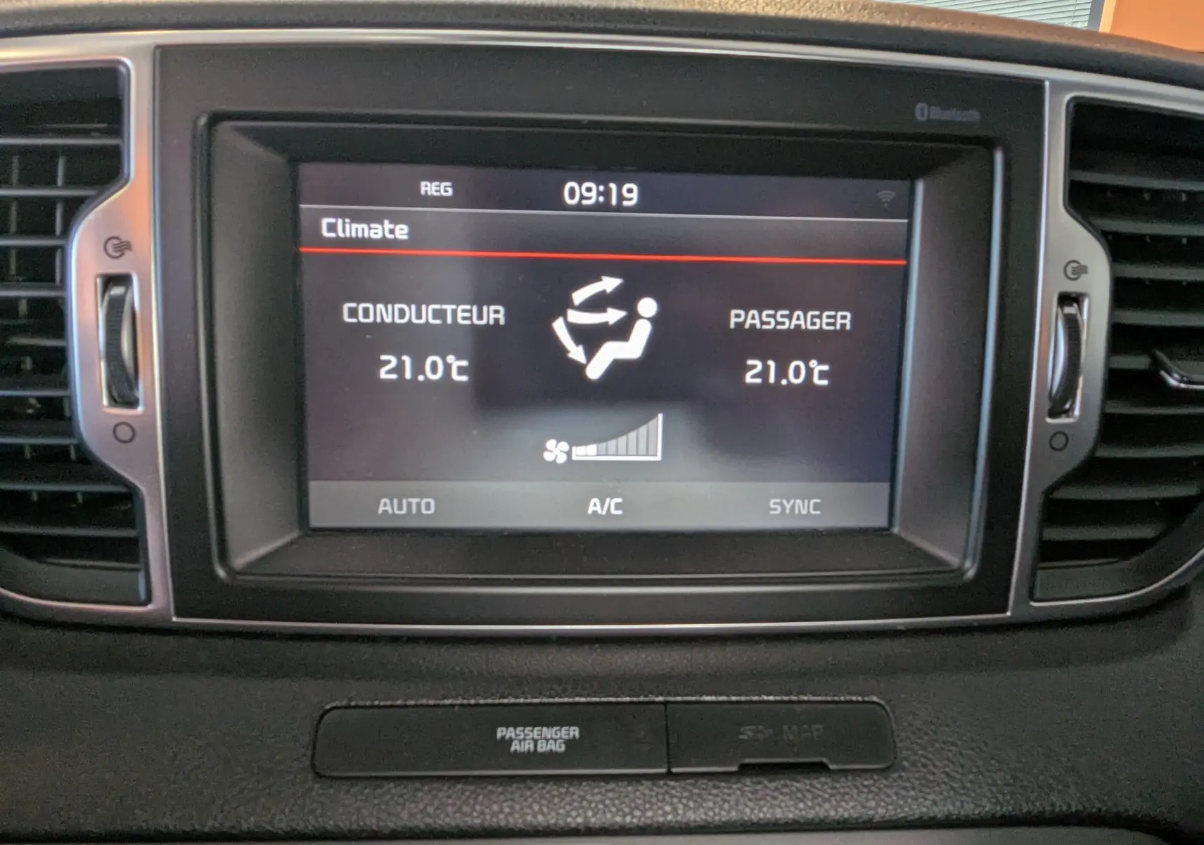 Écran central du tableau de bord du Kia Sportage 2016 affichant la climatisation bi-zone à 21°C pour conducteur et passager.