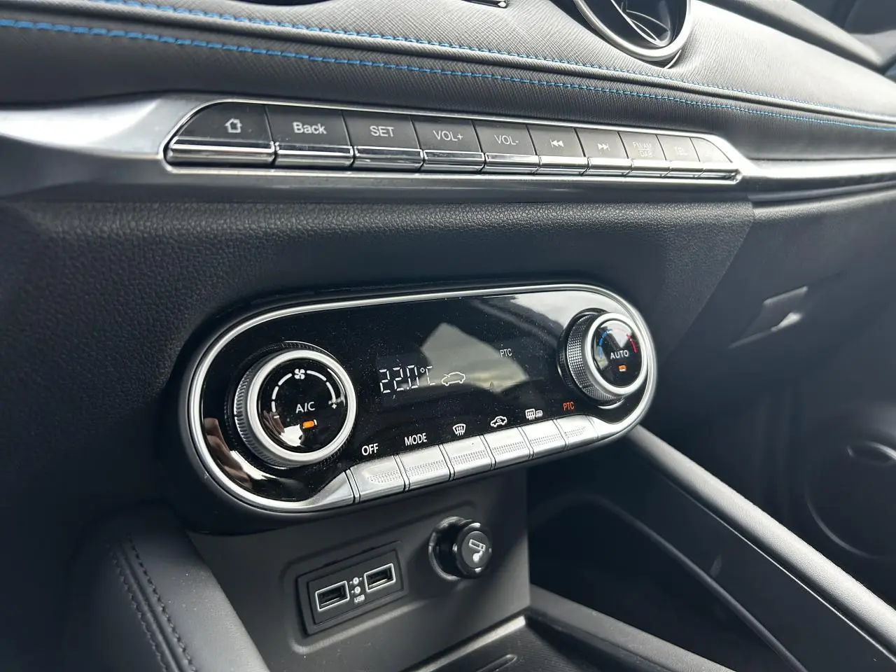 Détail de la console centrale noire avec commandes de climatisation et surpiqûres bleues du SERES 3 Luxury 2022.