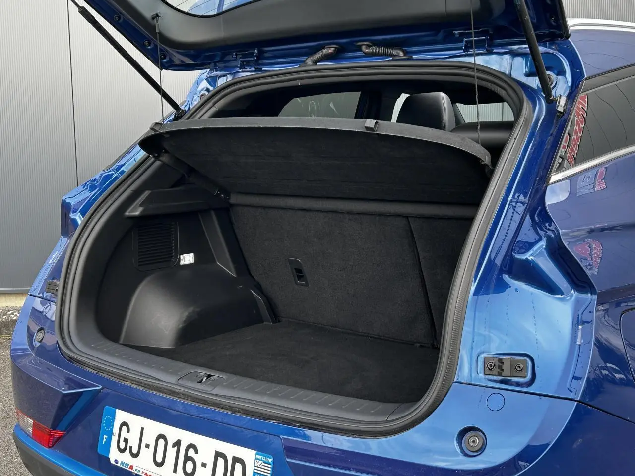 Coffre ouvert en bleu d'un SERES 3 163 Luxury électrique, vue arrière droite avec intérieur noir et cache-bagages.