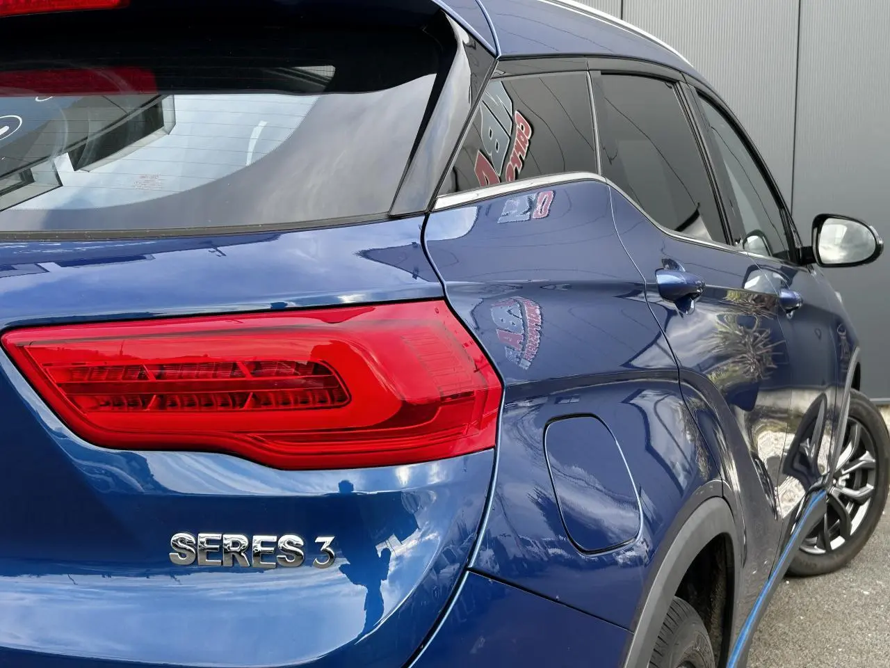 Vue 3/4 arrière droite du SUV électrique SERES 3 bleu avec feux arrière LED et vitres surteintées.