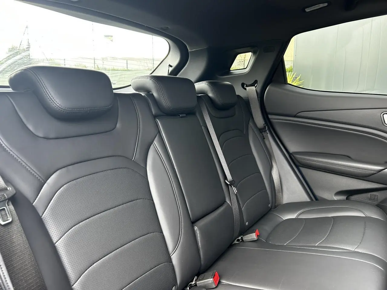 Vue intérieure sur les sièges arrière en cuir noir du SERES 3 163 Luxury, avec ceinture de sécurité et fenêtre latérale visible.