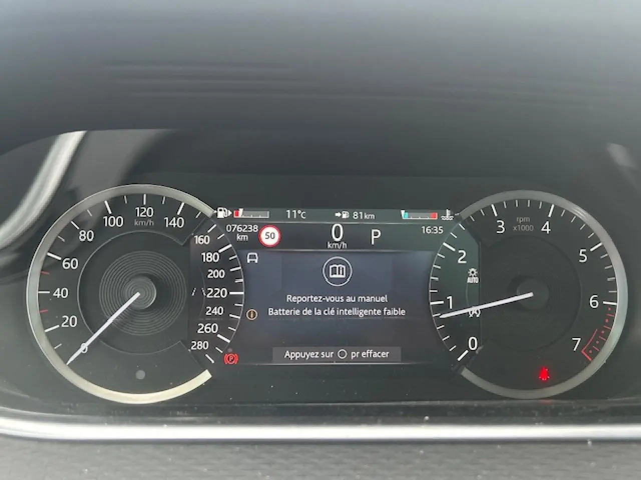 Tableau de bord numérique du Range Rover Evoque gris foncé, affichant vitesse, compte-tours et alertes.