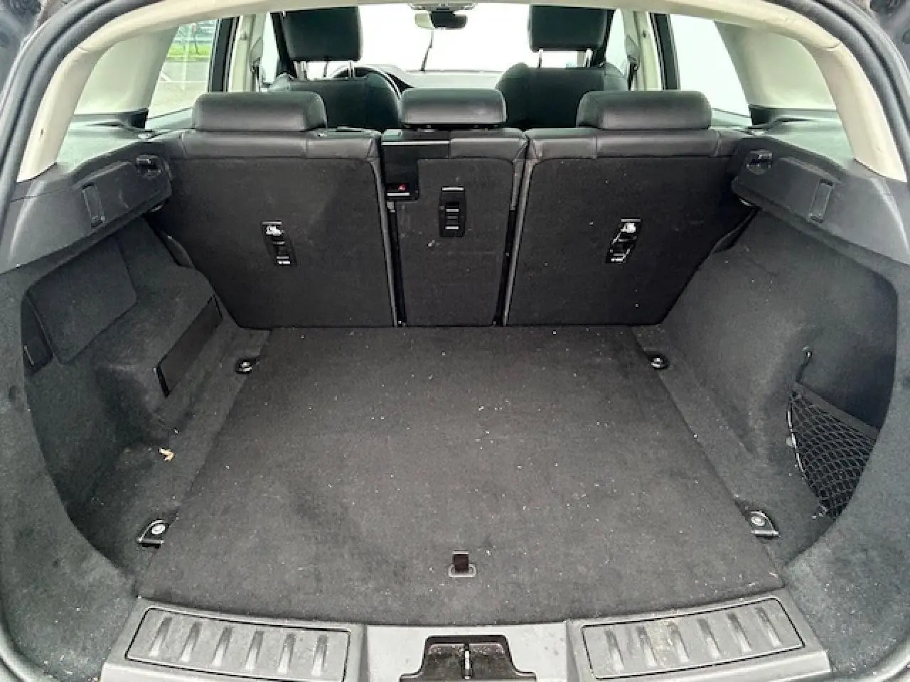 Coffre spacieux du Range Rover Evoque gris foncé, vue arrière avec sièges arrière relevés et habillage intérieur noir.