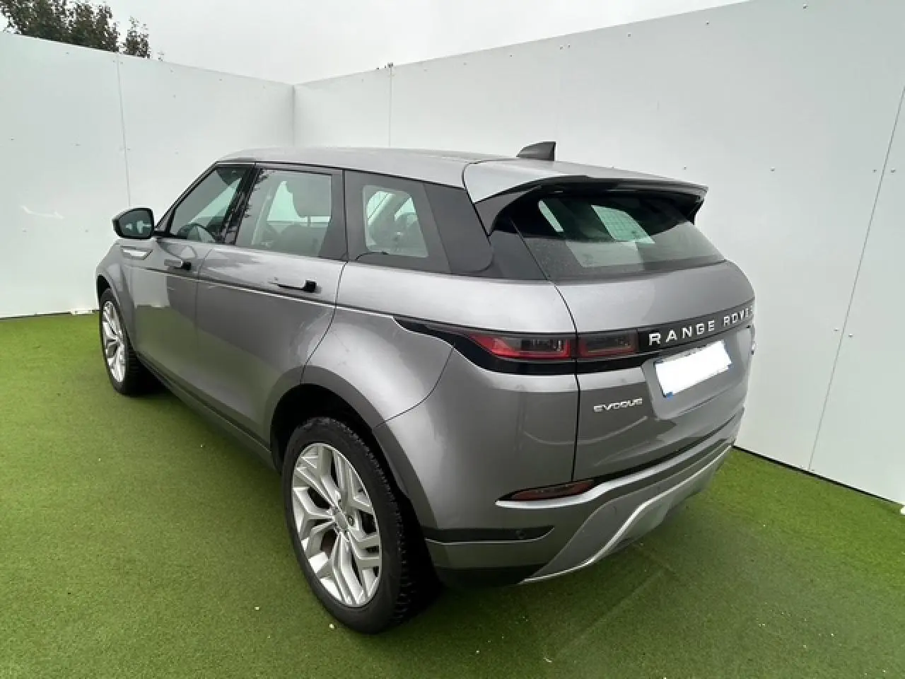 Vue 3/4 arrière droite d'un Range Rover Evoque gris foncé métallisé avec jantes 20 pouces et hayon électrique.