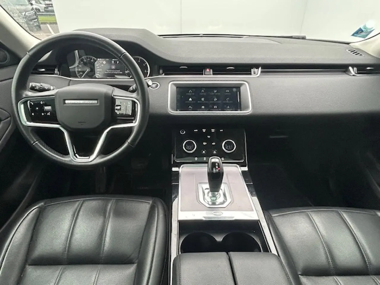 Intérieur noir du Range Rover Evoque 2022 vu de face, avec tableau de bord moderne et écran tactile central.