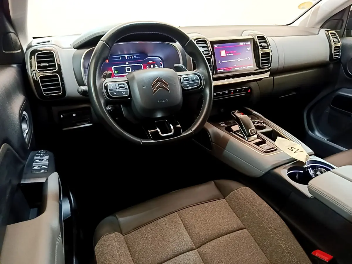 Intérieur du Citroën C5 Aircross 2020, vue côté conducteur, volant cuir noir et tableau de bord digital lumineux.