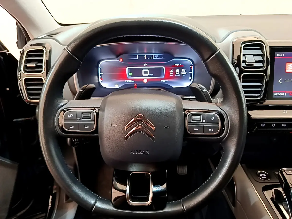 Vue rapprochée du volant cuir noir de la Citroën C5 Aircross 2020 avec tableau de bord digital et commandes intégrées.