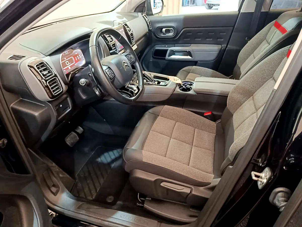 Intérieur avant droit du Citroën C5 Aircross noir 2020, volant cuir et sièges tissu gris avec console centrale moderne.
