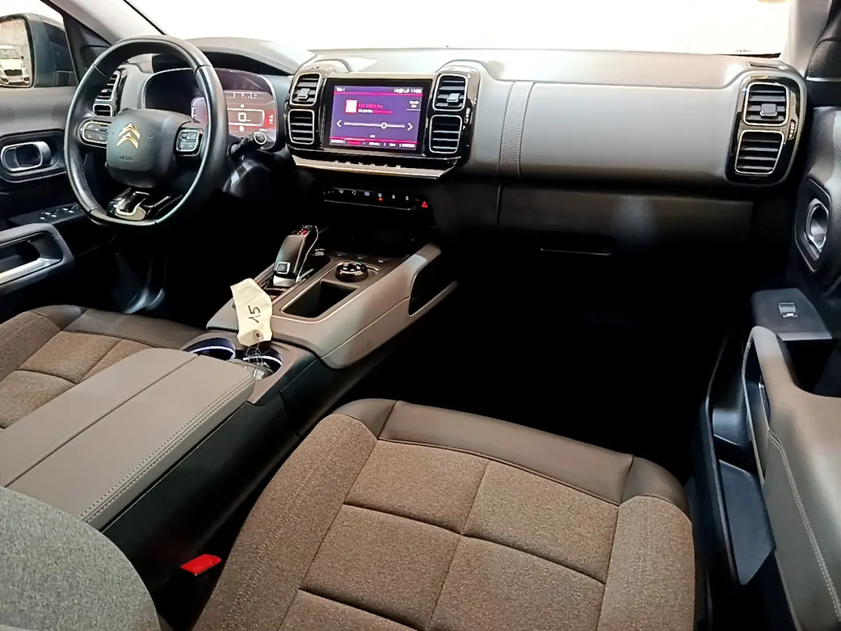 Intérieur du Citroën C5 Aircross 2020 avec tableau de bord noir et beige, volant cuir multifonctions et écran tactile central.