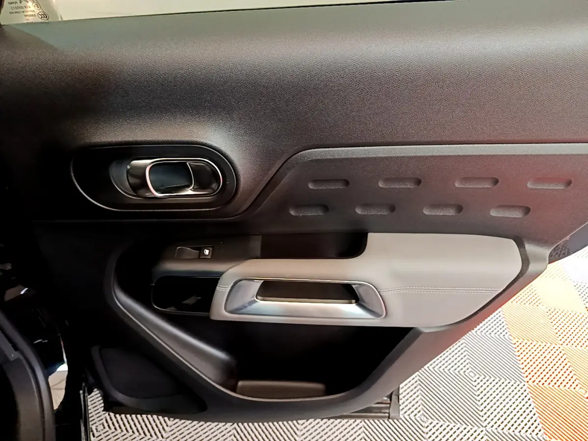 Gros plan sur la porte intérieure côté gauche du Citroën C5 Aircross noir, avec poignée argentée et garniture texturée.