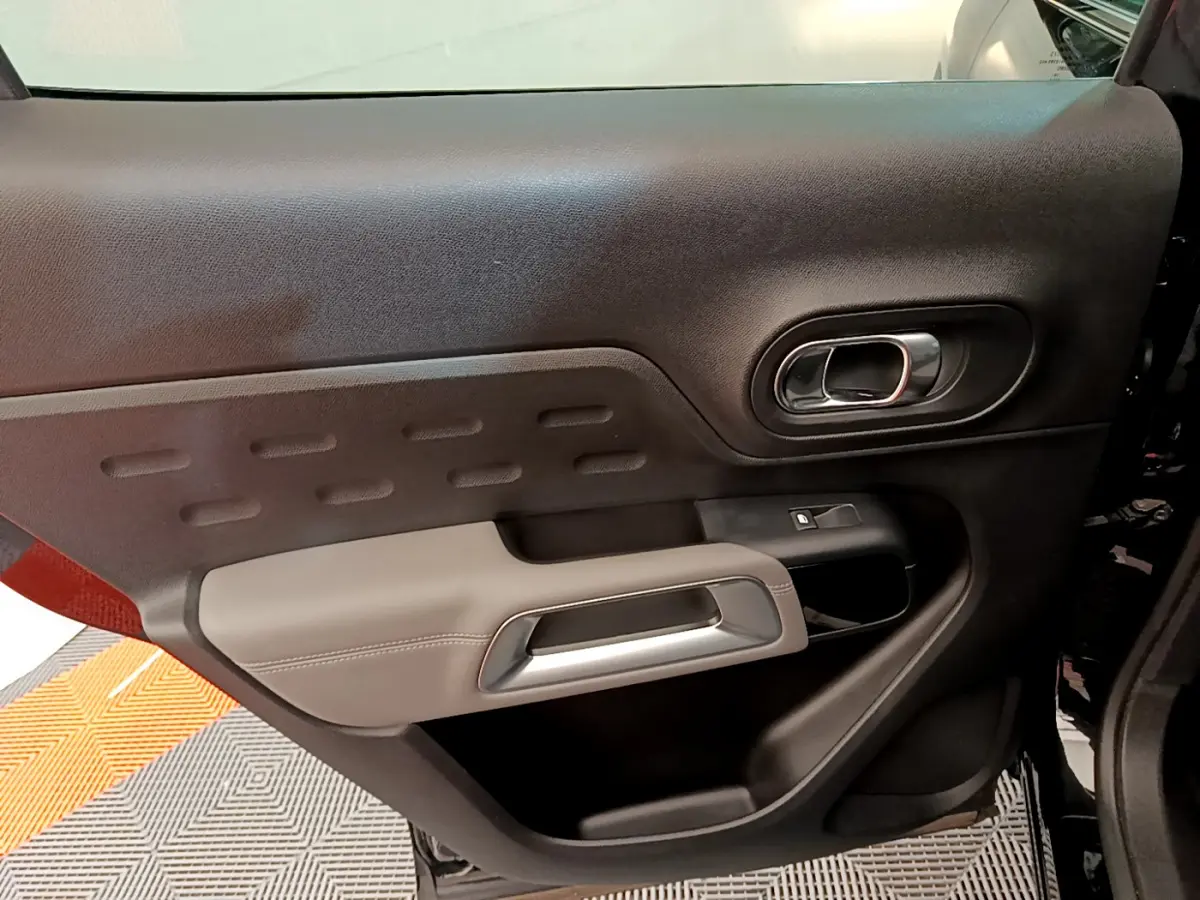Vue rapprochée de la porte côté gauche noire et grise du Citroën C5 Aircross avec poignée argentée et commande de vitre.