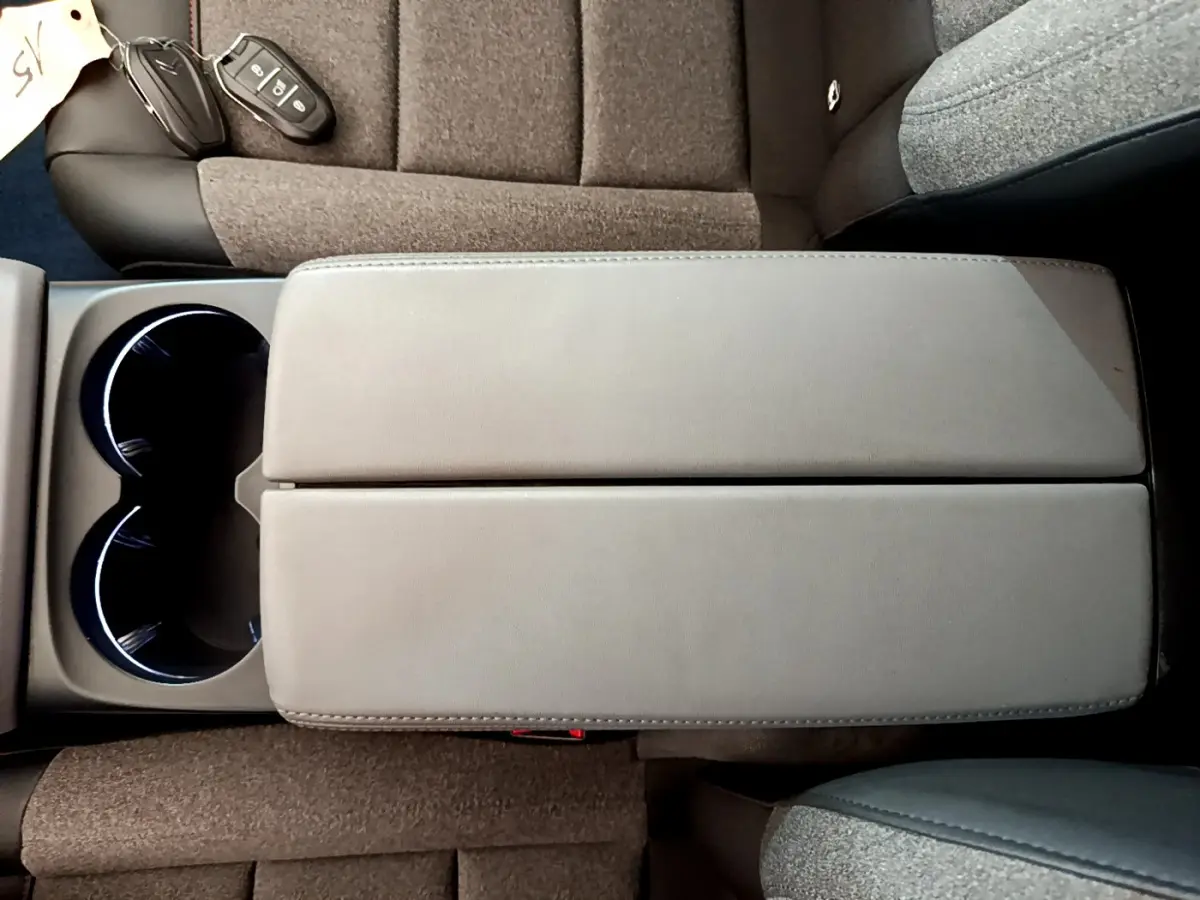 Vue plongeante sur l'accoudoir central gris et les sièges tissu marron du Citroën C5 Aircross 2020.