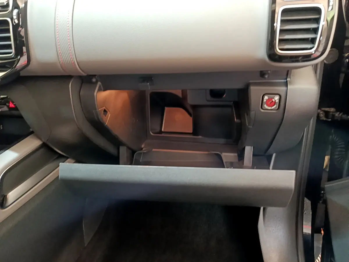 Ouverture de la boîte à gants côté passager du Citroën C5 Aircross noir, montrant le rangement intérieur et les finitions grises du tableau de bord.