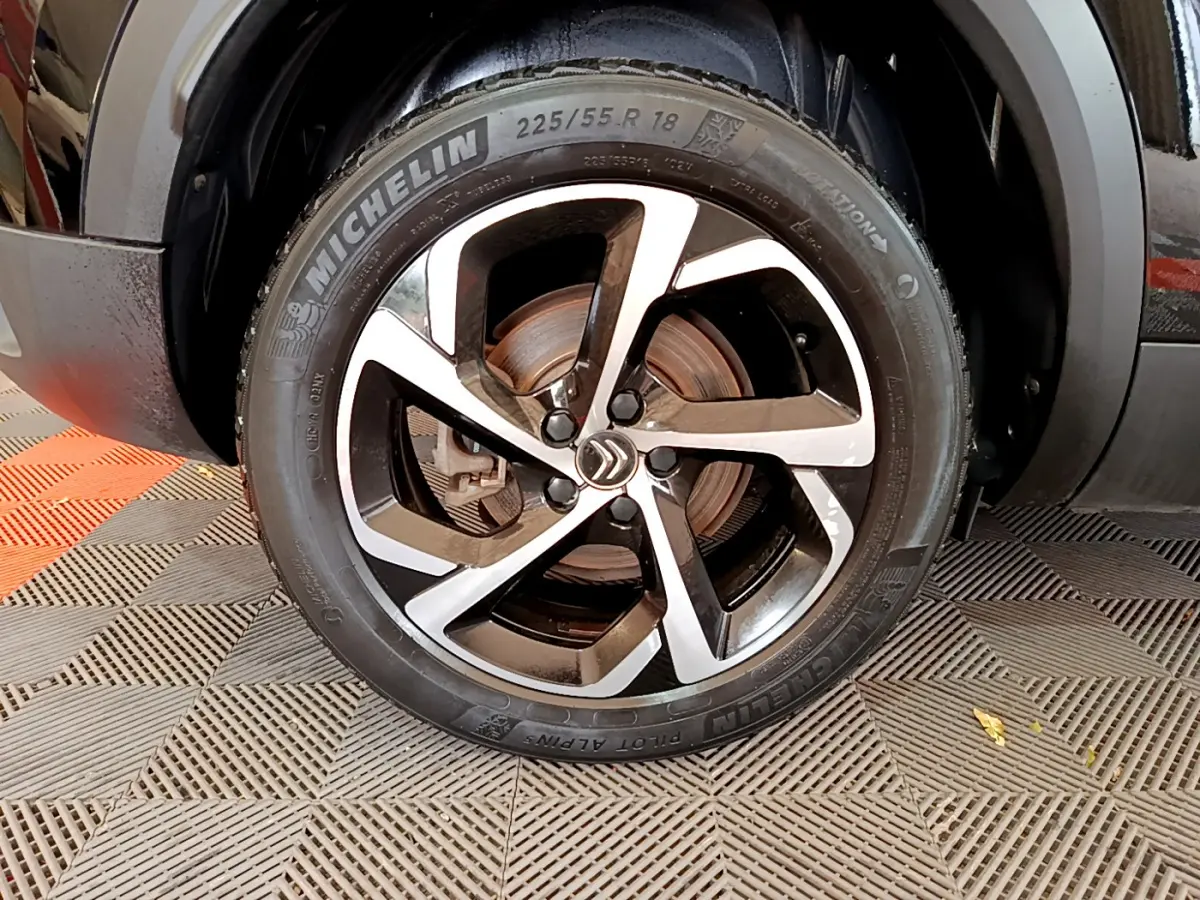 Gros plan sur la roue avant droite du Citroën C5 Aircross noir, avec jante alliage bicolore et pneu Michelin.