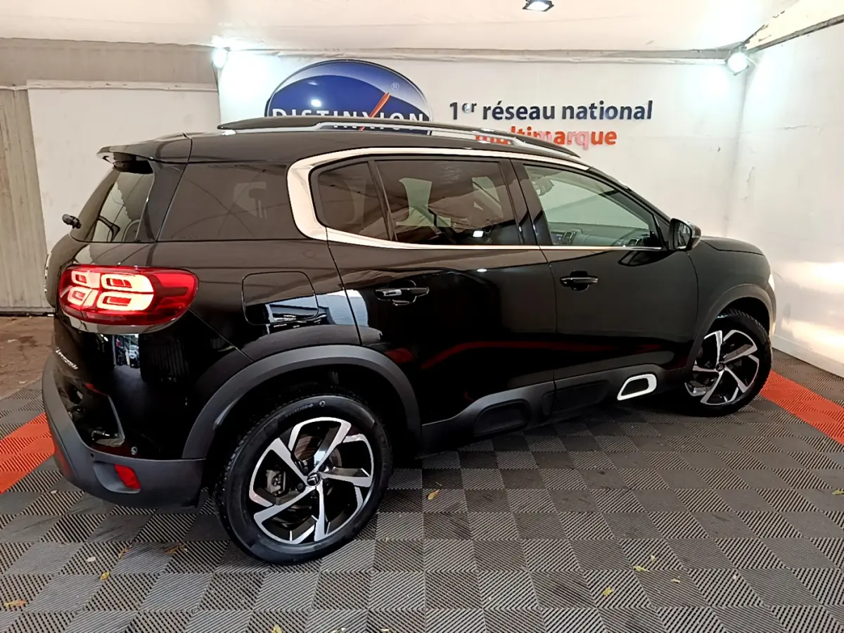 Vue 3/4 arrière droite d'un Citroën C5 Aircross noir avec jantes alliage et feux arrière LED allumés.