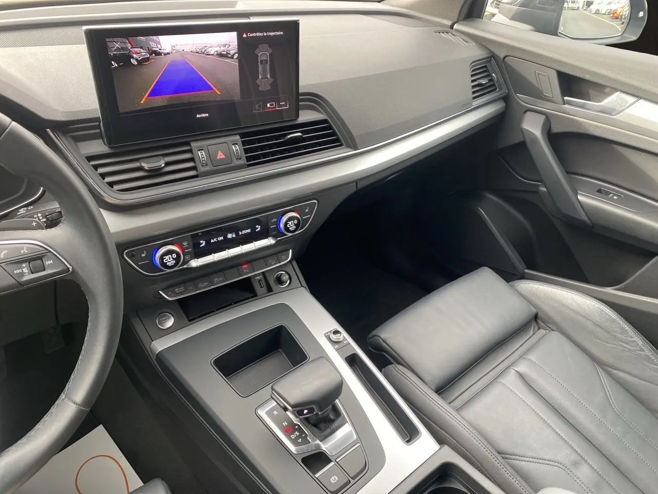 Vue intérieure côté passager de l'Audi Q5 noire 2022, avec écran multimédia affichant la caméra de recul.