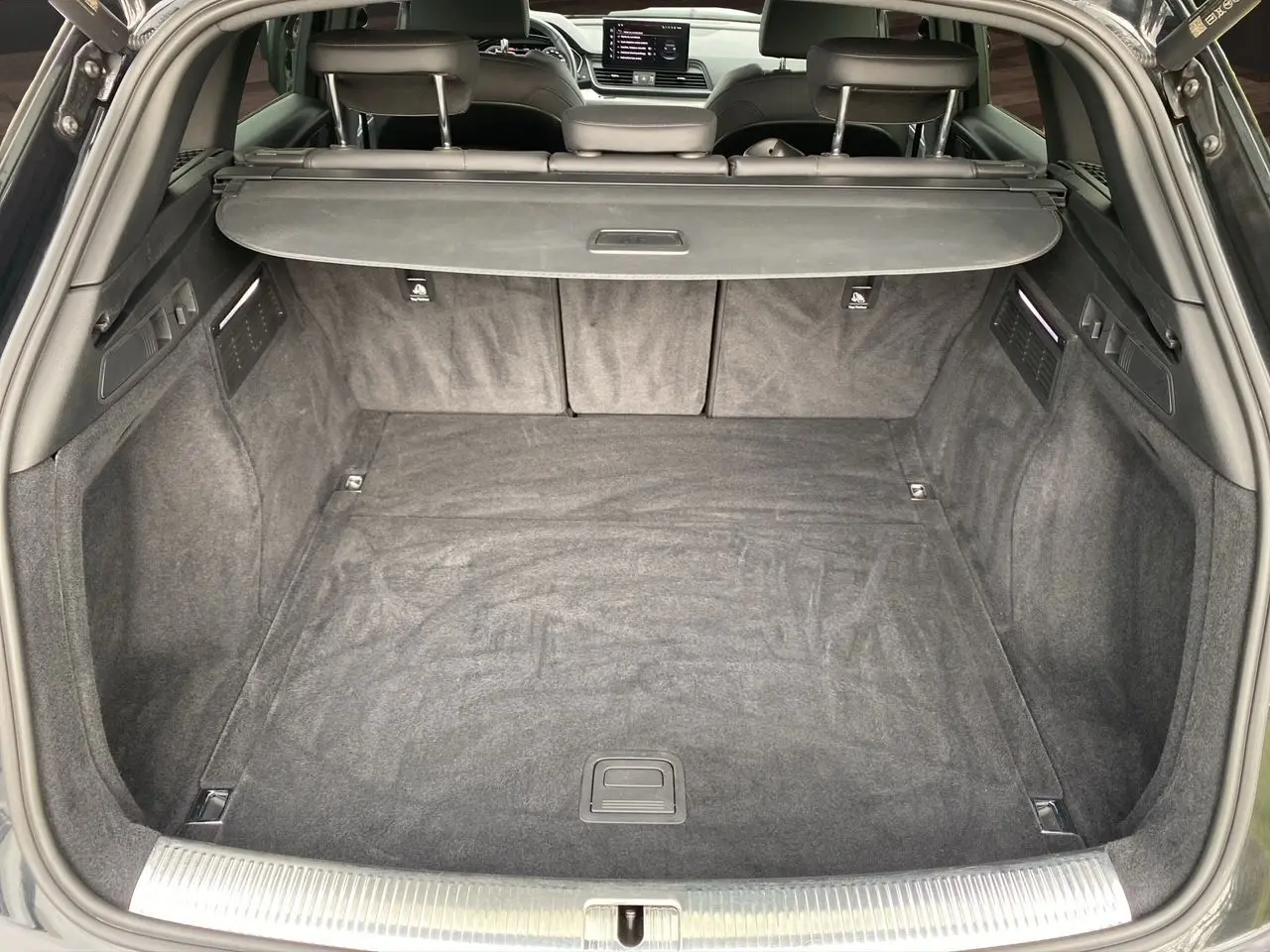 Vue du coffre arrière ouvert d’un Audi Q5 noir 2022, montrant un espace de chargement propre et spacieux avec cache-bagages.