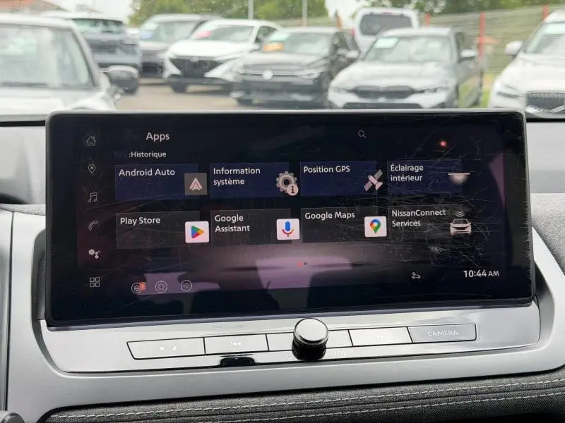 Vue intérieure centrée sur l'écran tactile multifonction du Nissan Qashqai blanc nacré, affichant les applications connectées.