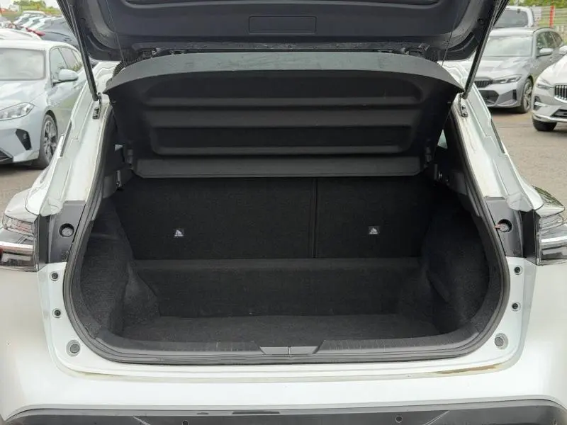 Coffre ouvert vu de l'arrière d'un Nissan Qashqai blanc nacré 2025, montrant l'espace de chargement vide et la tablette cache-bagages.