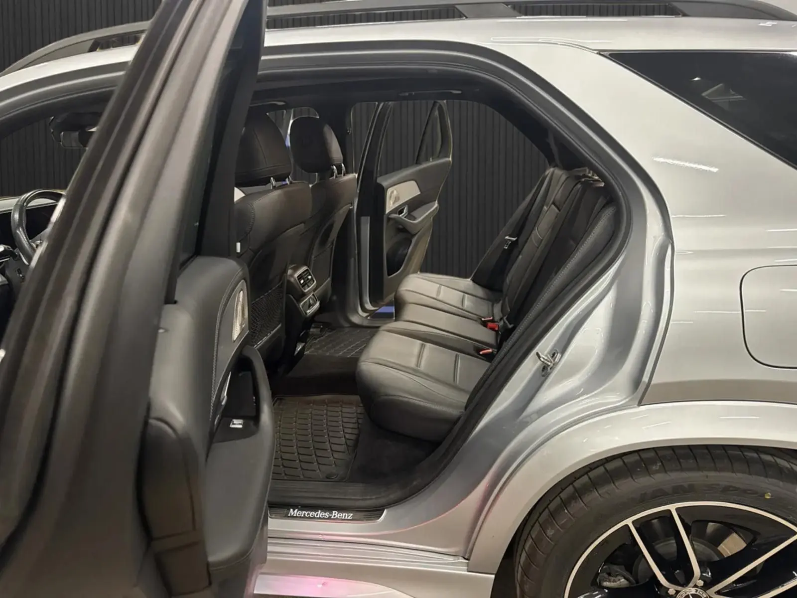 Vue côté droit arrière ouverte du Mercedes GLE 400 E Hybrid AMG Line 2023 argent métallisé, montrant les sièges arrière en cuir noir.