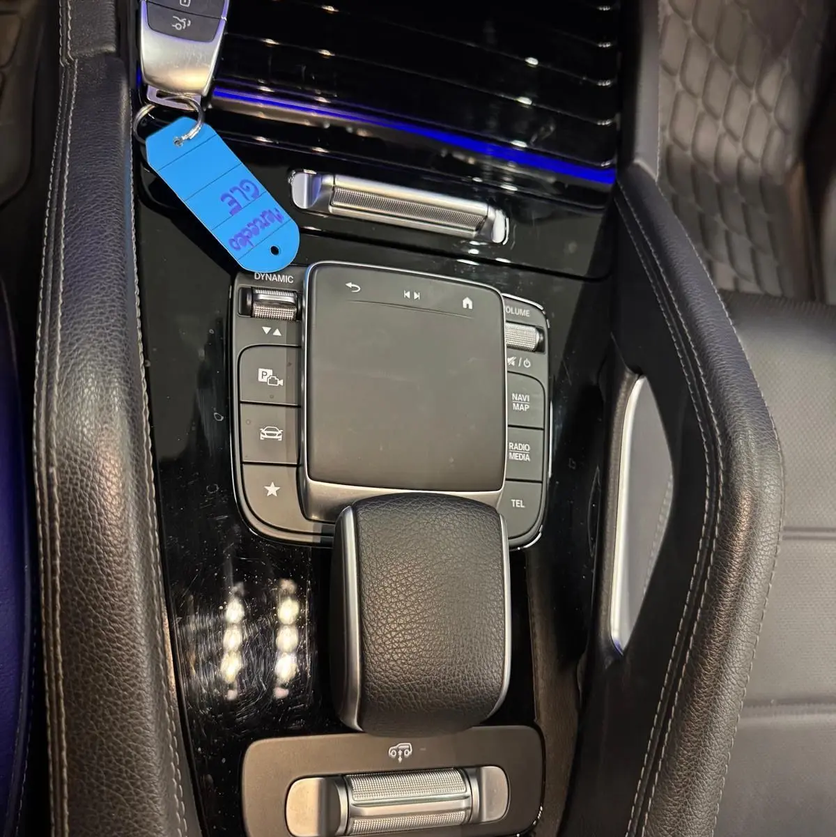 Vue rapprochée de la console centrale noire brillante du Mercedes GLE 400 E Hybrid AMG Line avec clé et cuir noir.
