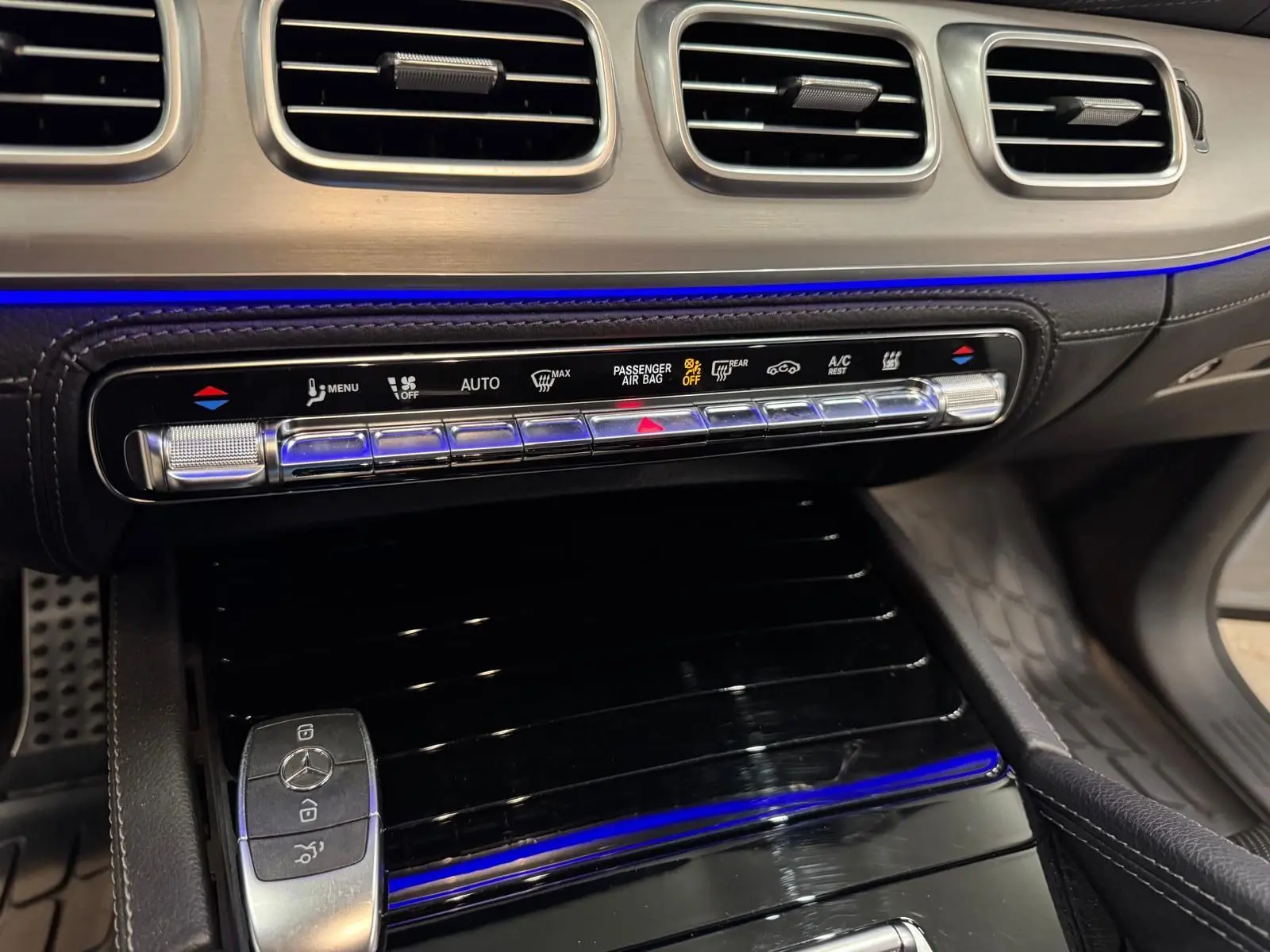 Détail de la console centrale du Mercedes GLE 400 E Hybrid AMG Line 2023, avec éclairage d’ambiance bleu et finitions argentées.