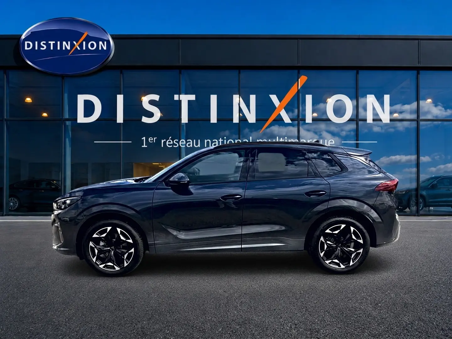 Vue latérale droite d'une CUPRA TERRAMAR 1.5 etsi hybrid gris Timanfaya avec jantes 19 pouces devant une vitrine Distinxion.