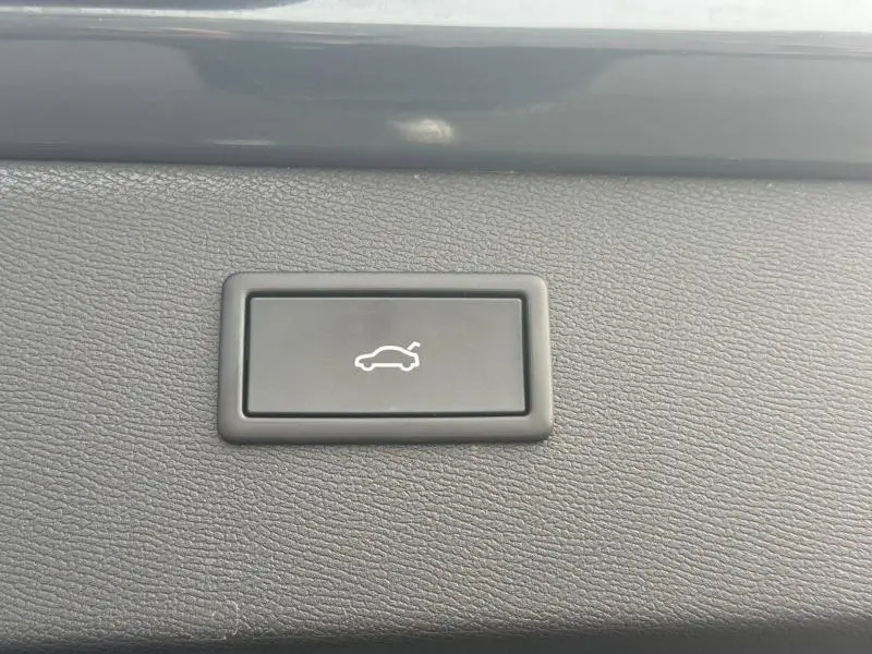 Bouton noir de commande d'ouverture électrique du coffre sur tableau de bord d'une CUPRA Formentor bleu.