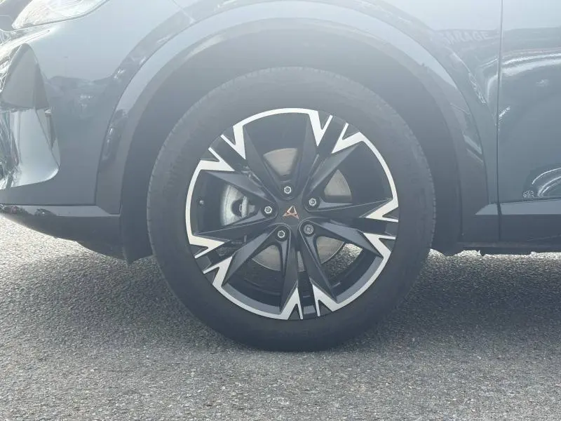 Gros plan sur la roue avant gauche de la CUPRA Formentor bleu avec jante alu noire et argentée au design anguleux.