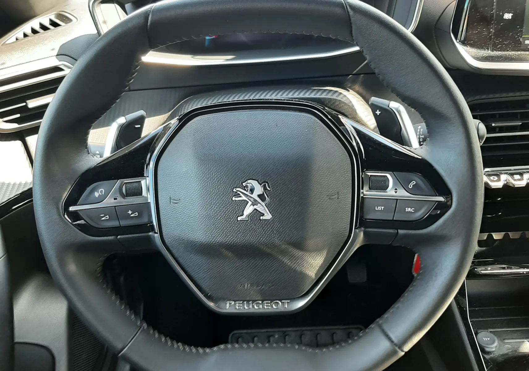 Vue rapprochée du volant noir du Peugeot 2008 2023 avec commandes intégrées et tableau de bord digital.