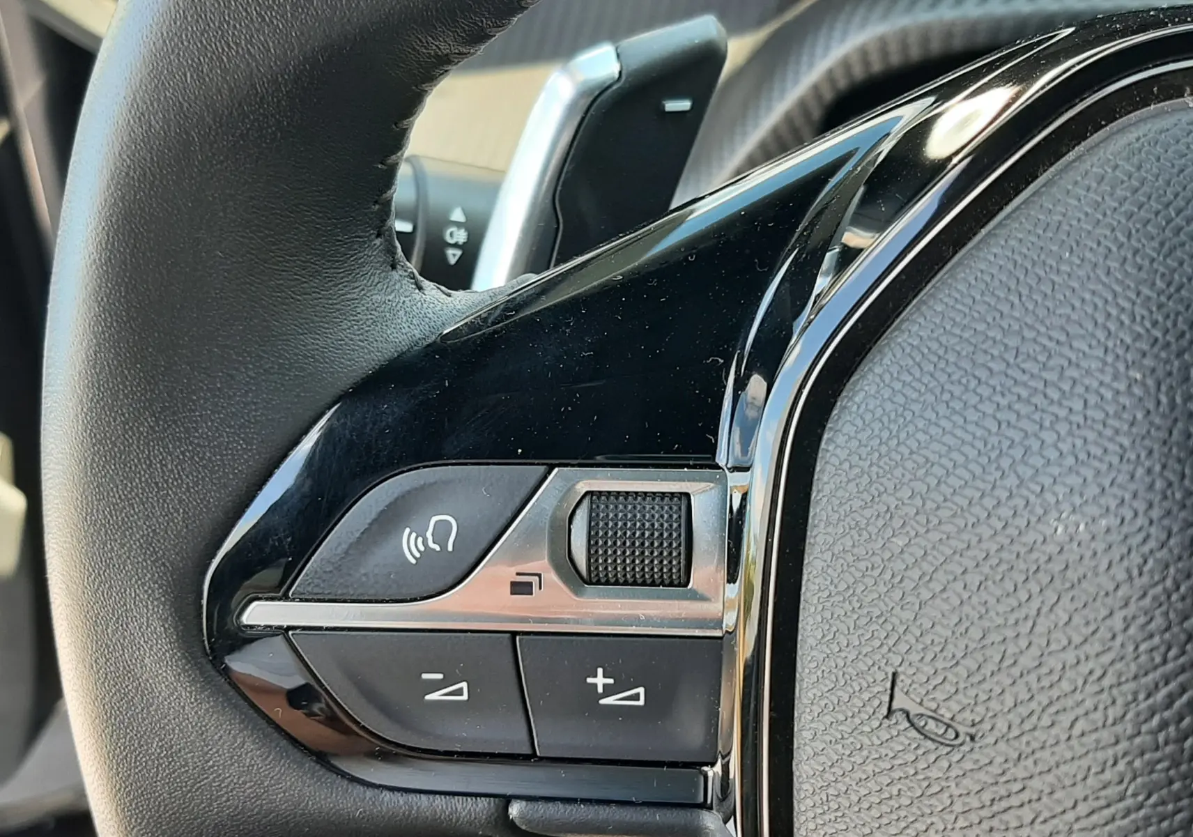 Gros plan sur la commande gauche du volant noir du Peugeot 2008 2023, avec boutons de volume et molette tactile.