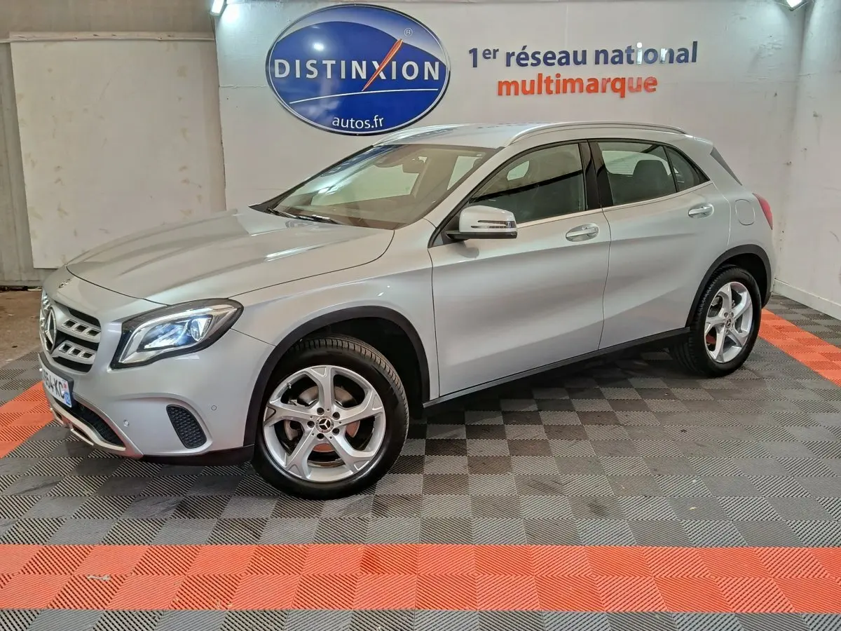 Mercedes GLA 200 d Business gris clair vue 3/4 avant droit, avec jantes alliage et feux LED allumés en intérieur showroom.