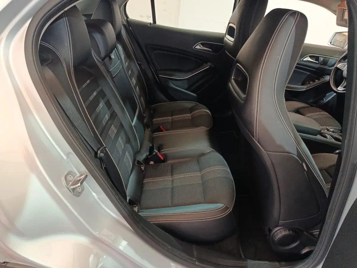 Vue intérieure côté arrière droit du Mercedes GLA 200 d gris clair, sièges tissu noir avec surpiqûres blanches.